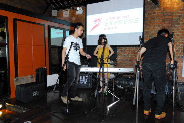 Musicians perform on stage with Hong Kong Express branding projected behind them.