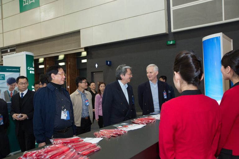 People interacting at a service counter with staff in red uniforms.