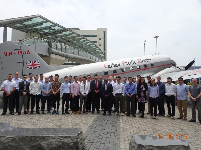 Group of people posing in front of a vintage Cathay Pacific Airways airplane.