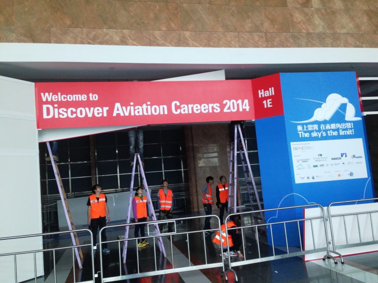 Workers installing event signage for Discover Aviation Careers 2014 at Hall 1E.