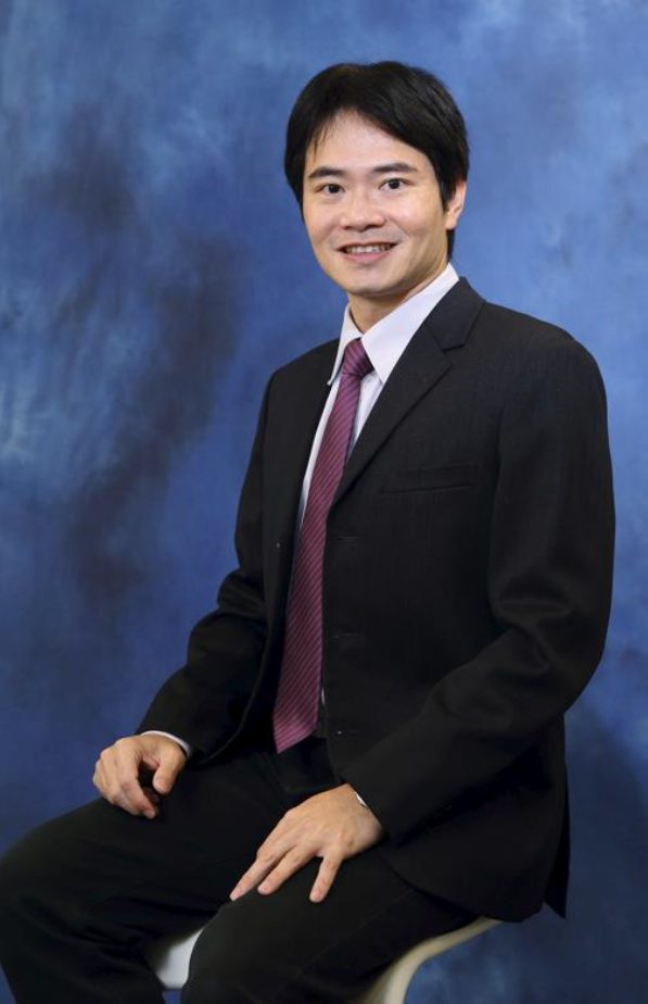 Raymond Tong in professional attire smiling against blue background