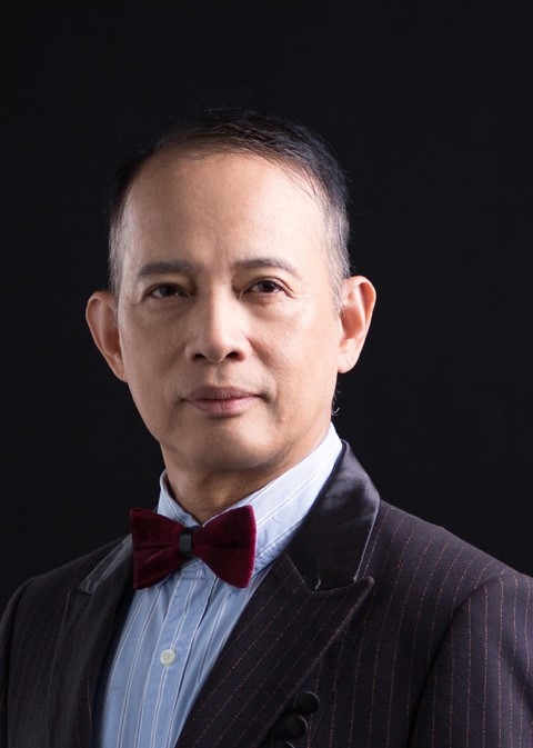 Man in pinstripe suit and red bow tie against black background
