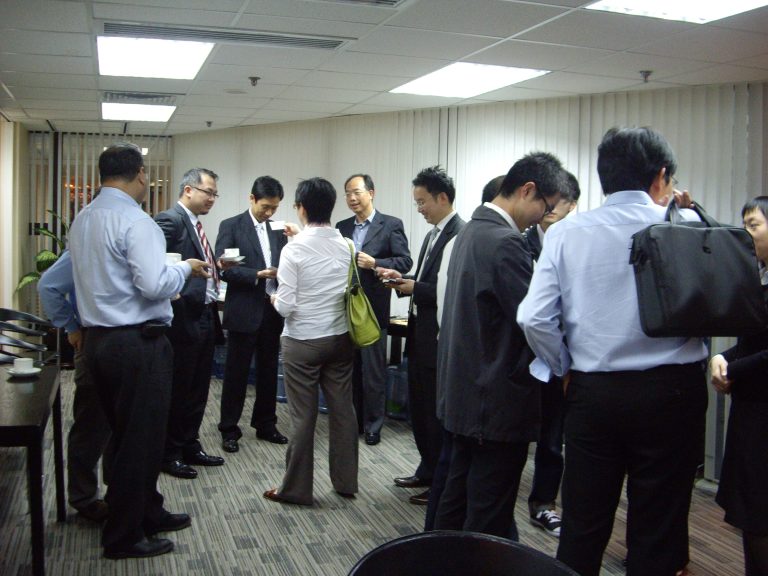 Business professionals networking in an office breakroom setting.