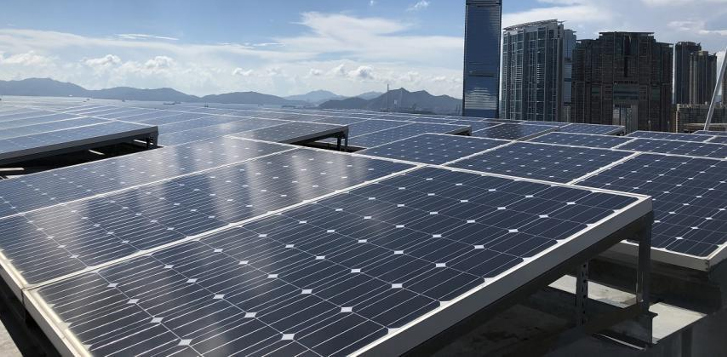Solar panels installed on a rooftop with city skyline and mountains in background