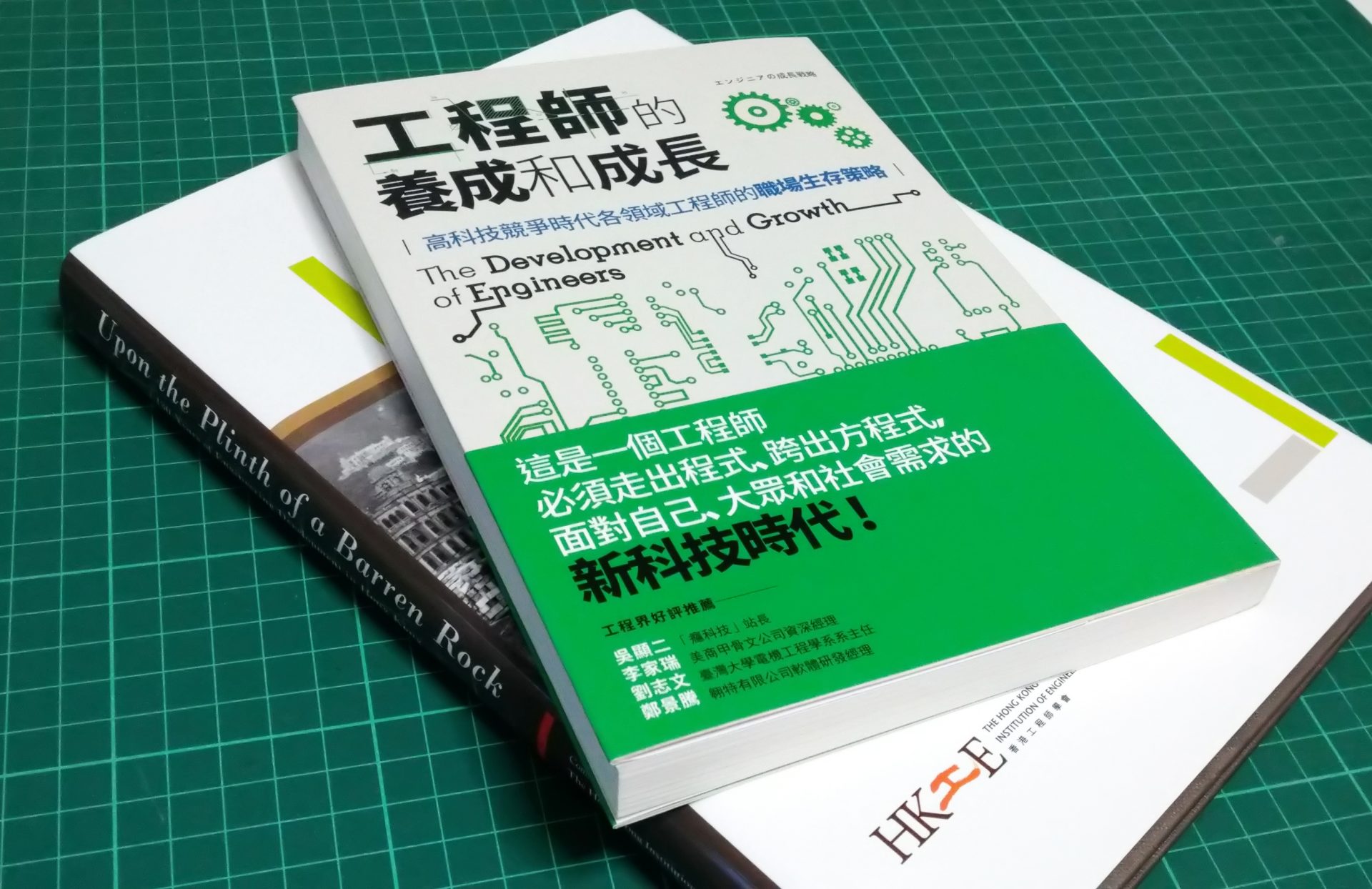 Two books on engineering and professional growth resting on a green cutting mat.
