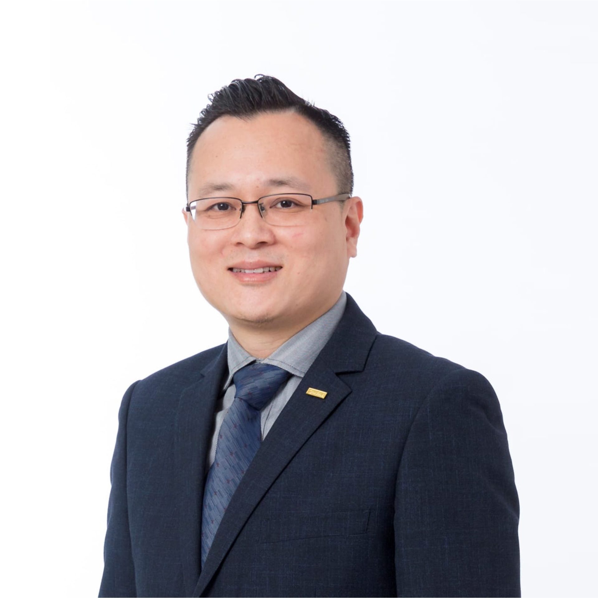 Portrait of Brian CHENG wearing glasses, suit, and tie against white background