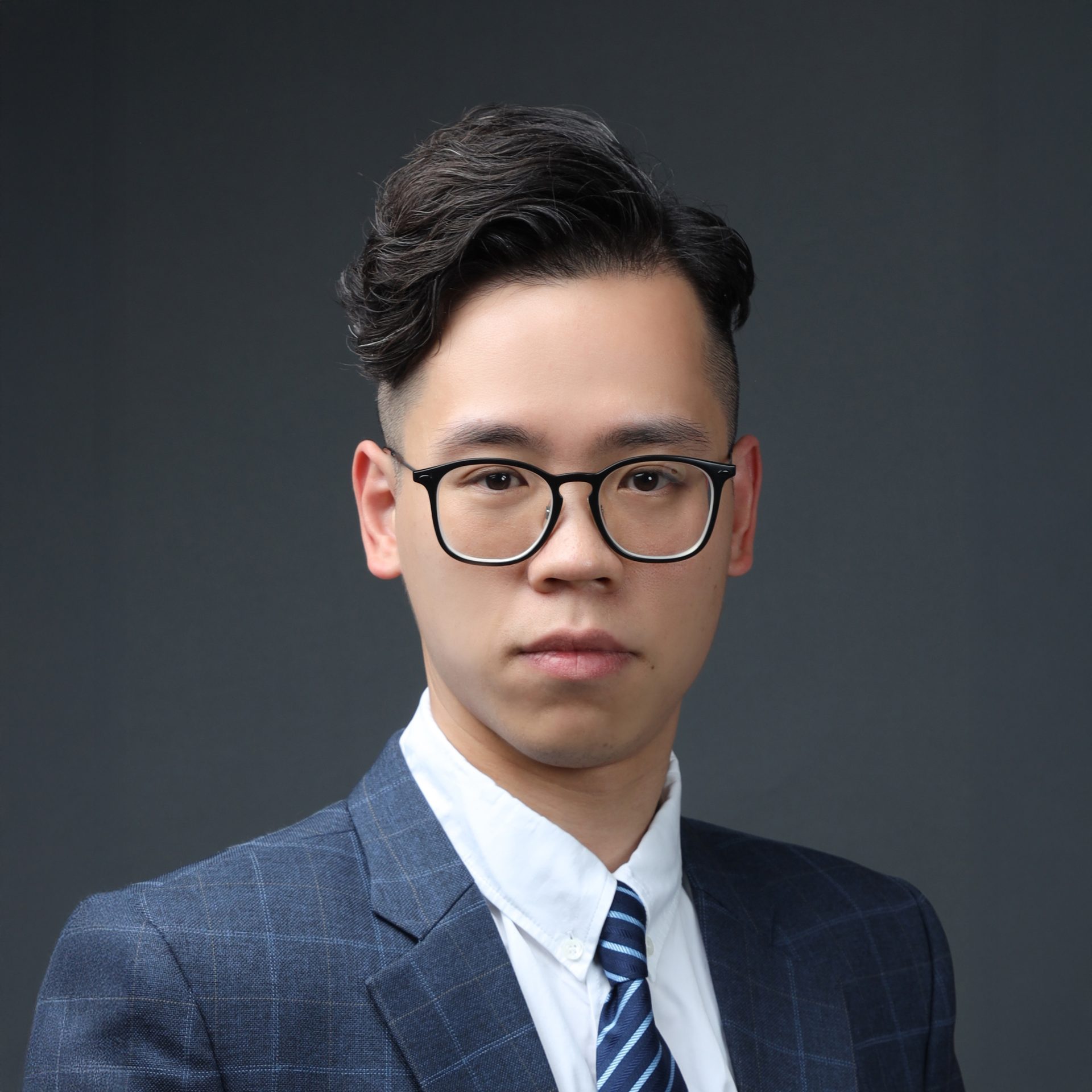 Portrait of Ir Derek Chan Tak Shing wearing glasses, suit, and striped tie.
