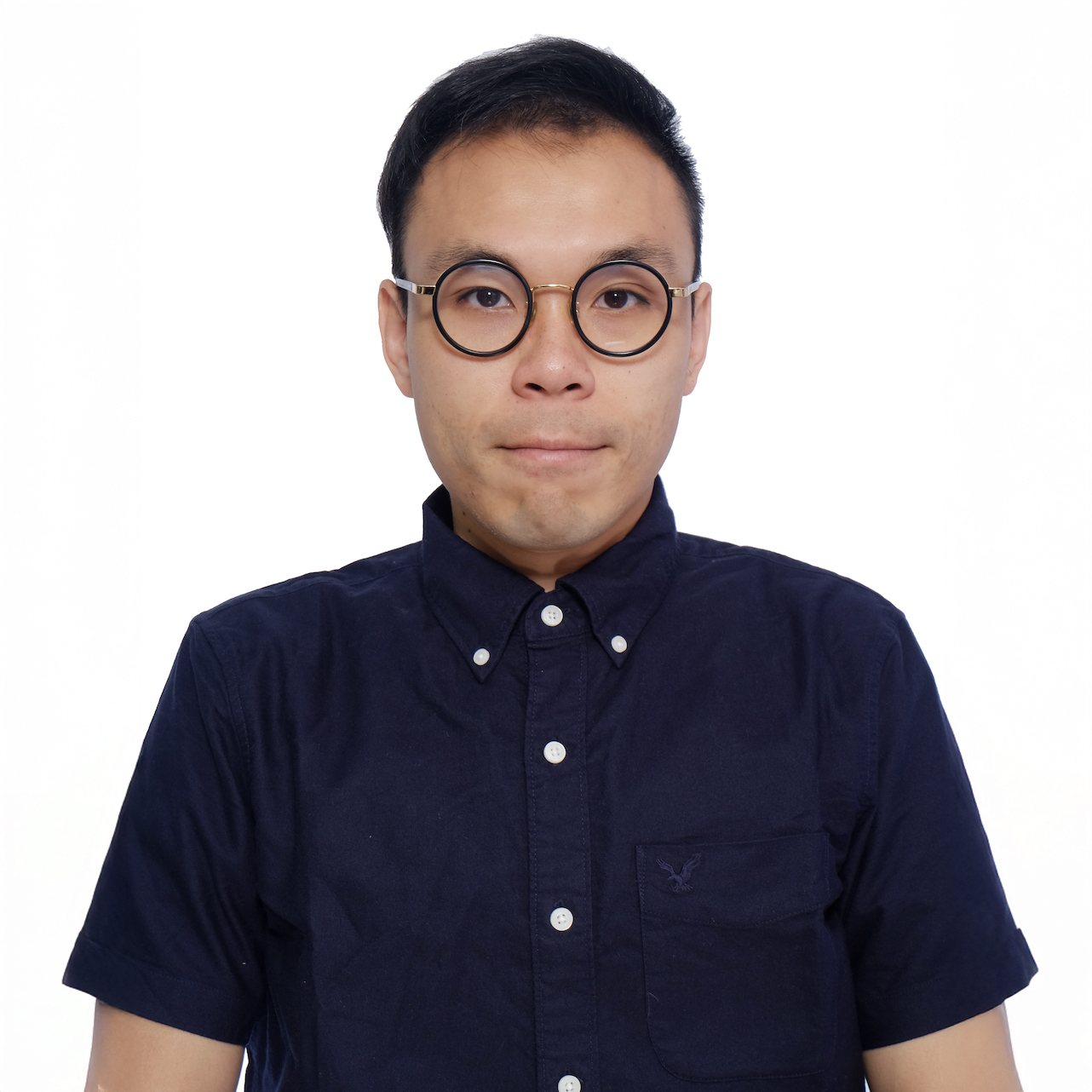 Man with round glasses wearing a dark blue button-up shirt against a white background.