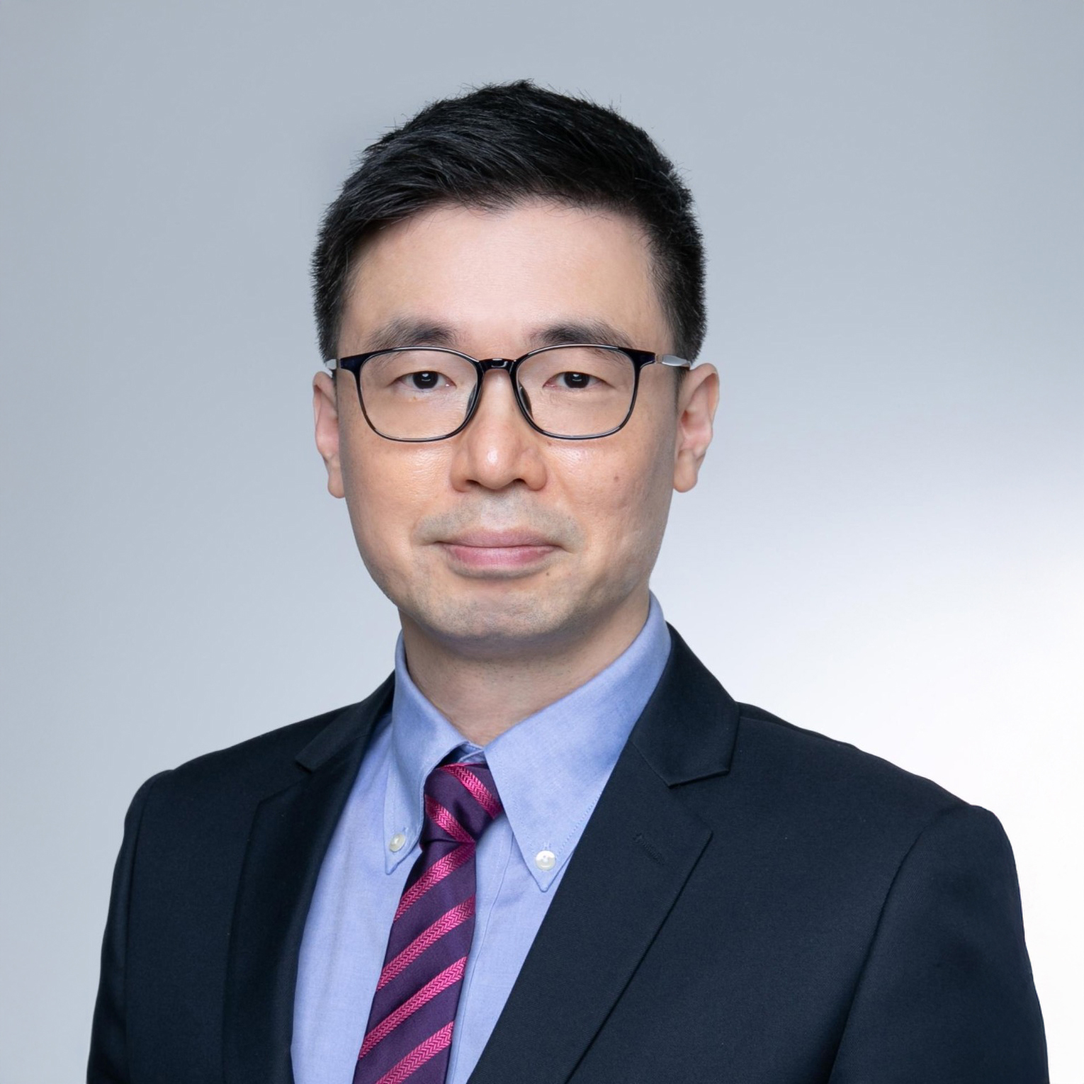 Portrait of Ir Howard YEUNG wearing glasses, suit, and striped tie.