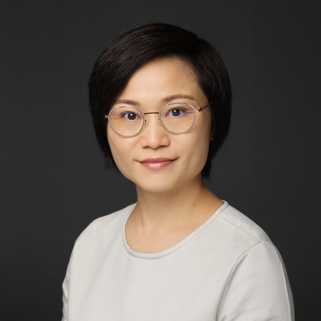 Portrait of a woman with short dark hair and round glasses, wearing a light-colored top.