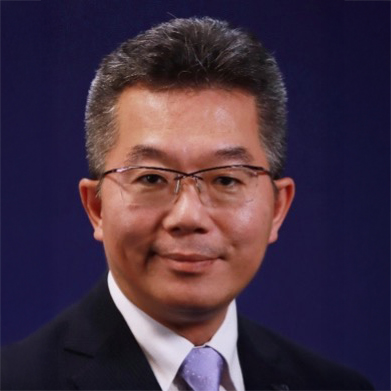 Portrait of Ir KC LAU, wearing glasses and suit, smiling against a blue background.