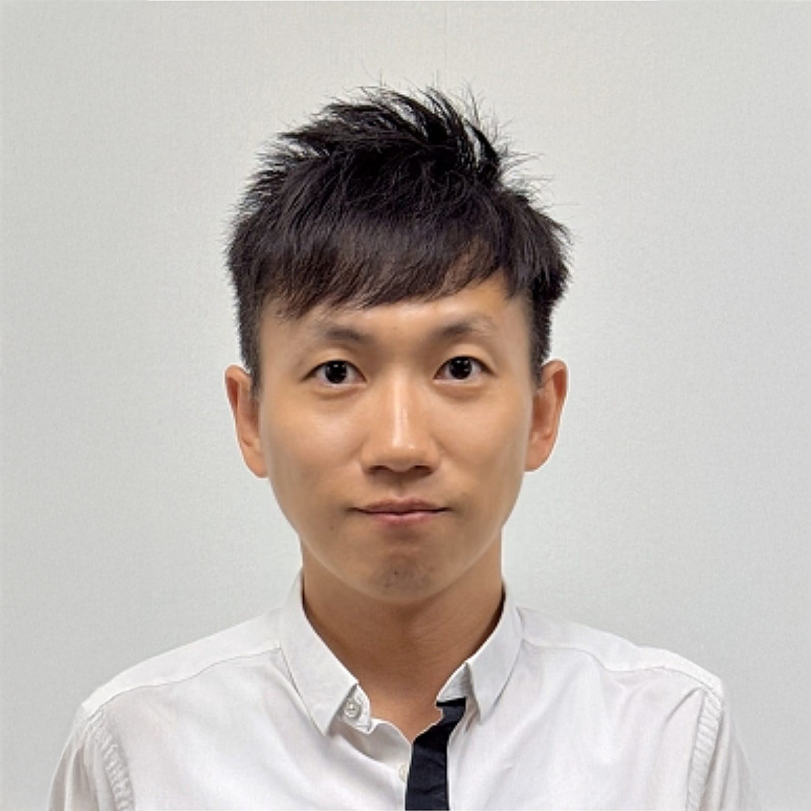 Portrait of a man with dark hair wearing a white collared shirt.