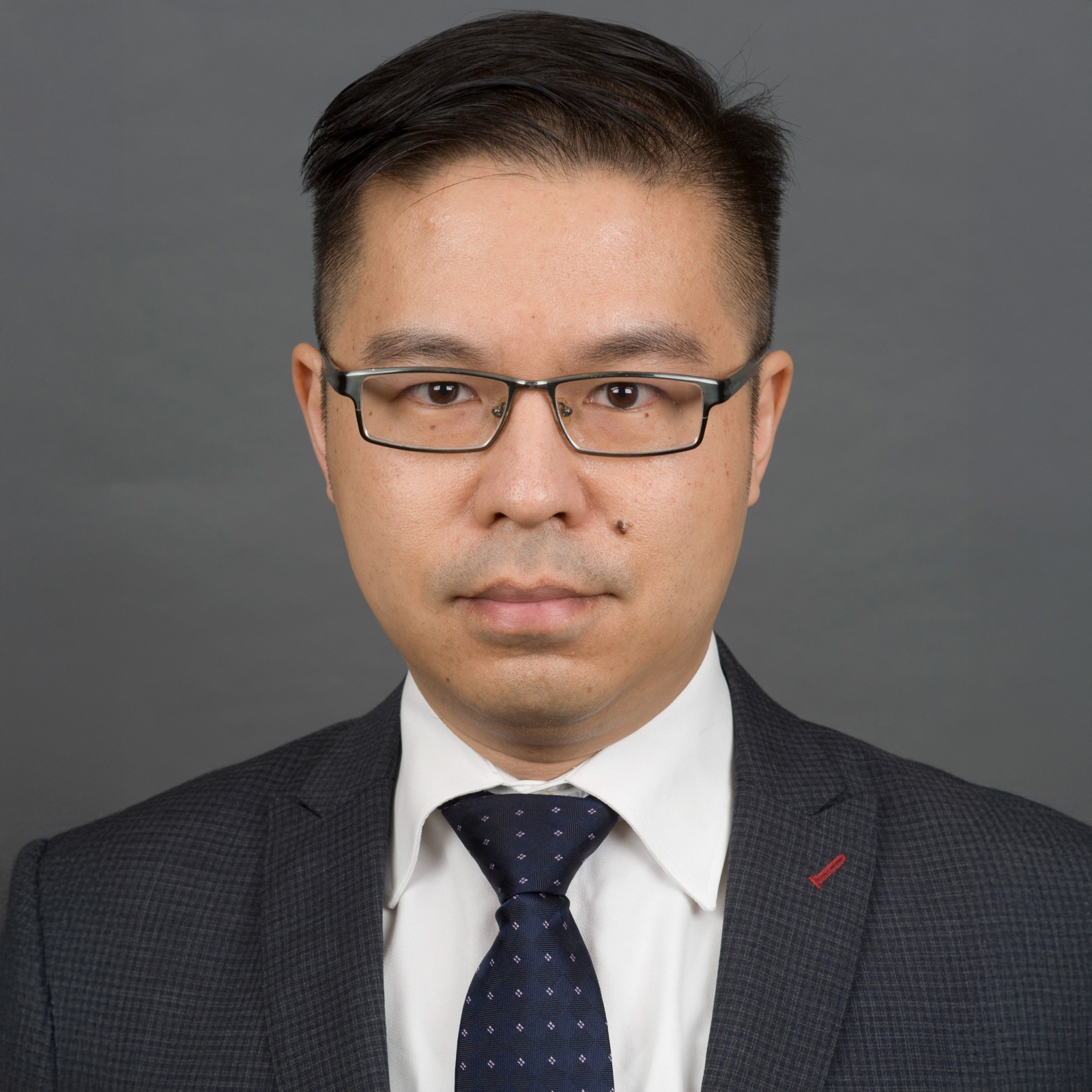 Portrait of Vincent LEUNG wearing glasses, suit, and patterned tie.