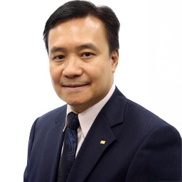 Professional headshot of a smiling man in a dark suit and tie.