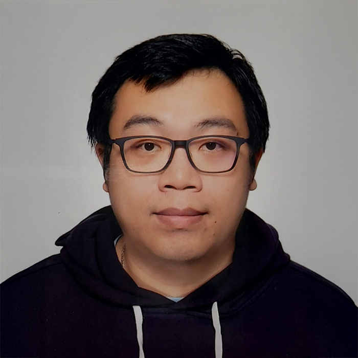 Portrait of Mr Joseph KWAN wearing glasses and a dark hoodie.