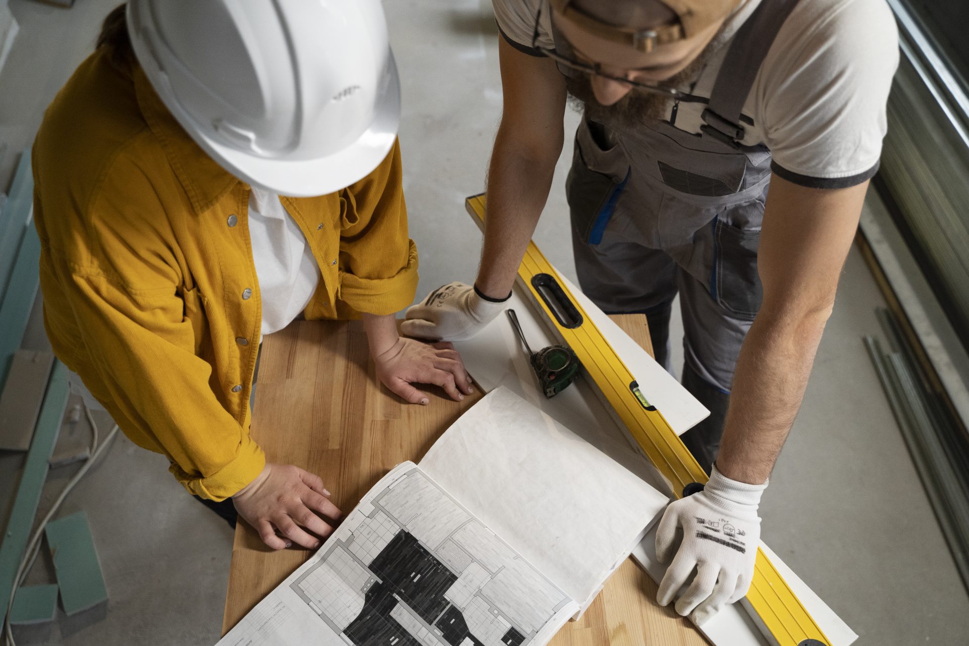 Two workers reviewing floor plans and measuring tools for apartment renovation.