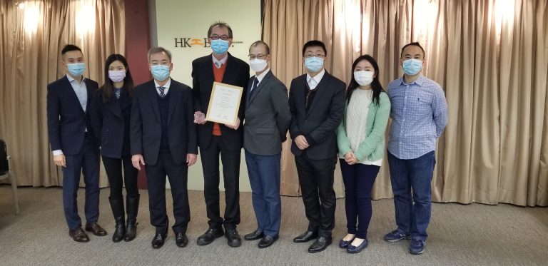 Group of eight people wearing masks posing with certificate indoors