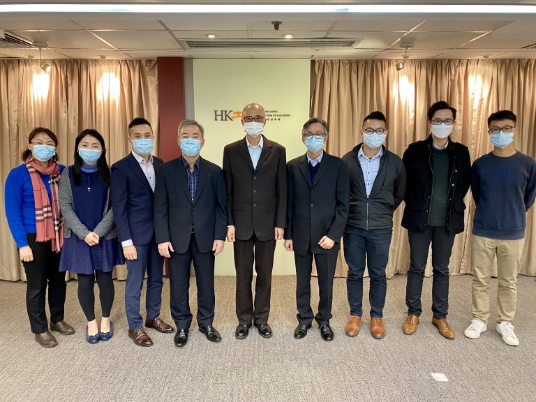 Group of eight people wearing masks posing for photo in front of Hong Kong Institution of Engineers sign.