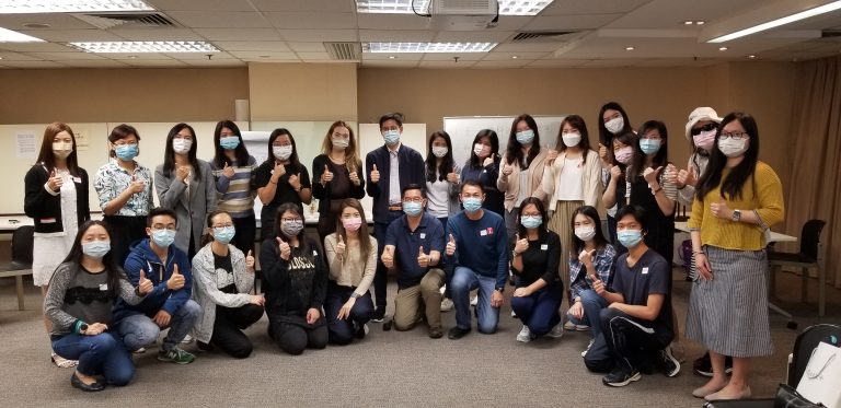 Group of people wearing masks giving thumbs up in a classroom setting