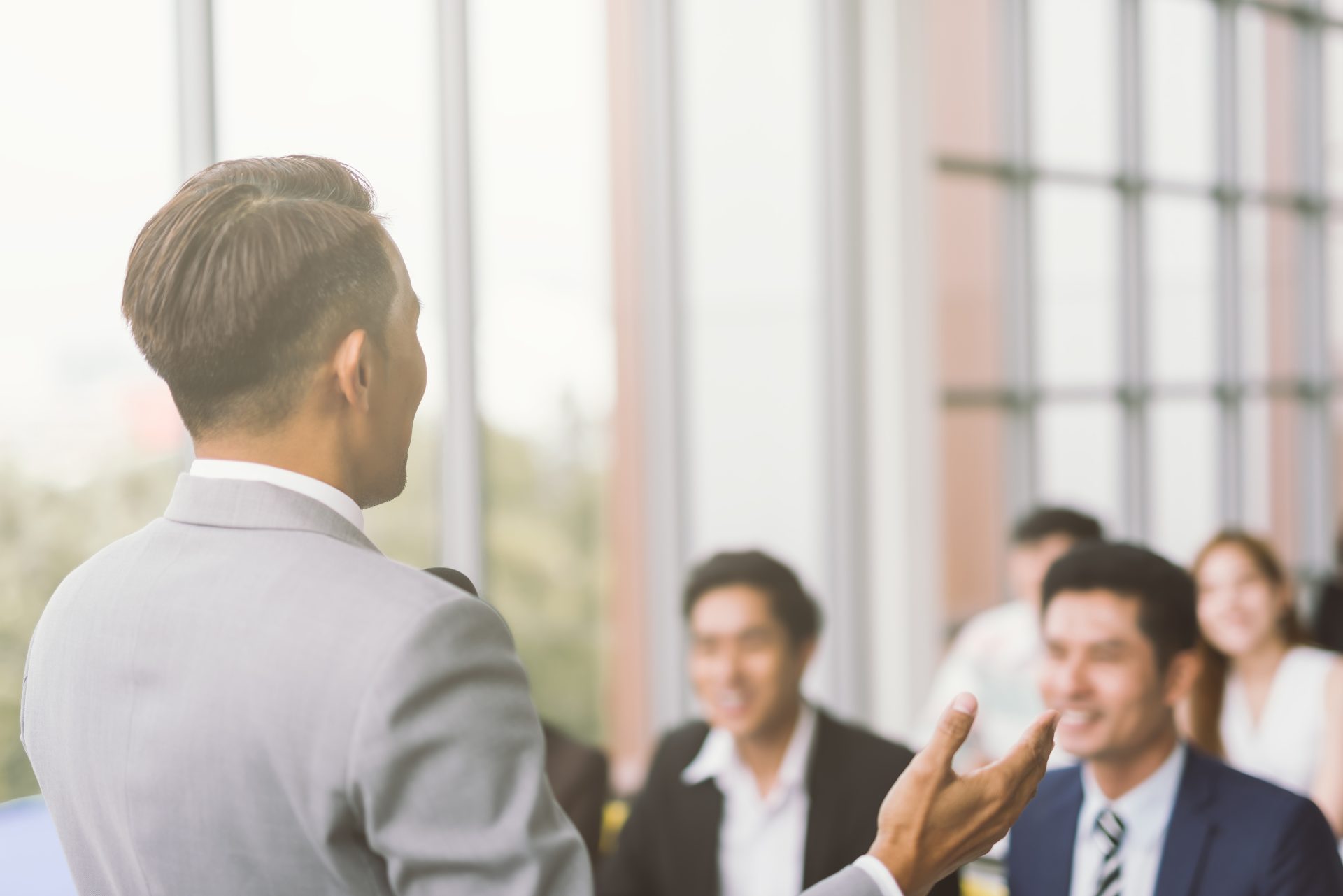 Businessman presenting to colleagues in office, viewed from behind.