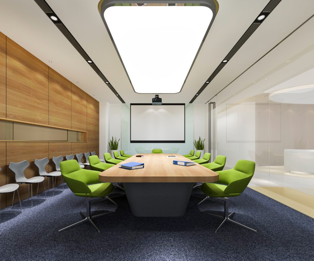 Modern conference room with long wooden table, green chairs, and projector screen.