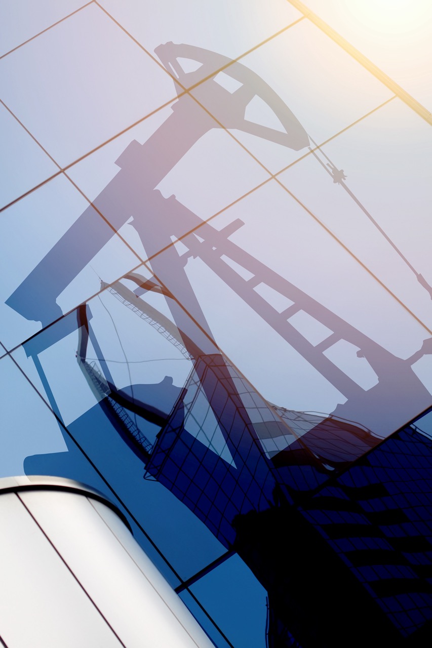 Modern office building glass reflecting oil derrick silhouette with sunlight glow.