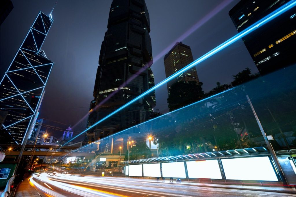 Nighttime cityscape with illuminated skyscrapers and light trails from traffic.