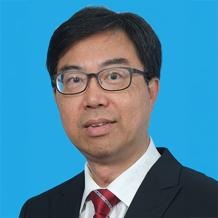Headshot of a man with glasses wearing a suit and red tie against blue background