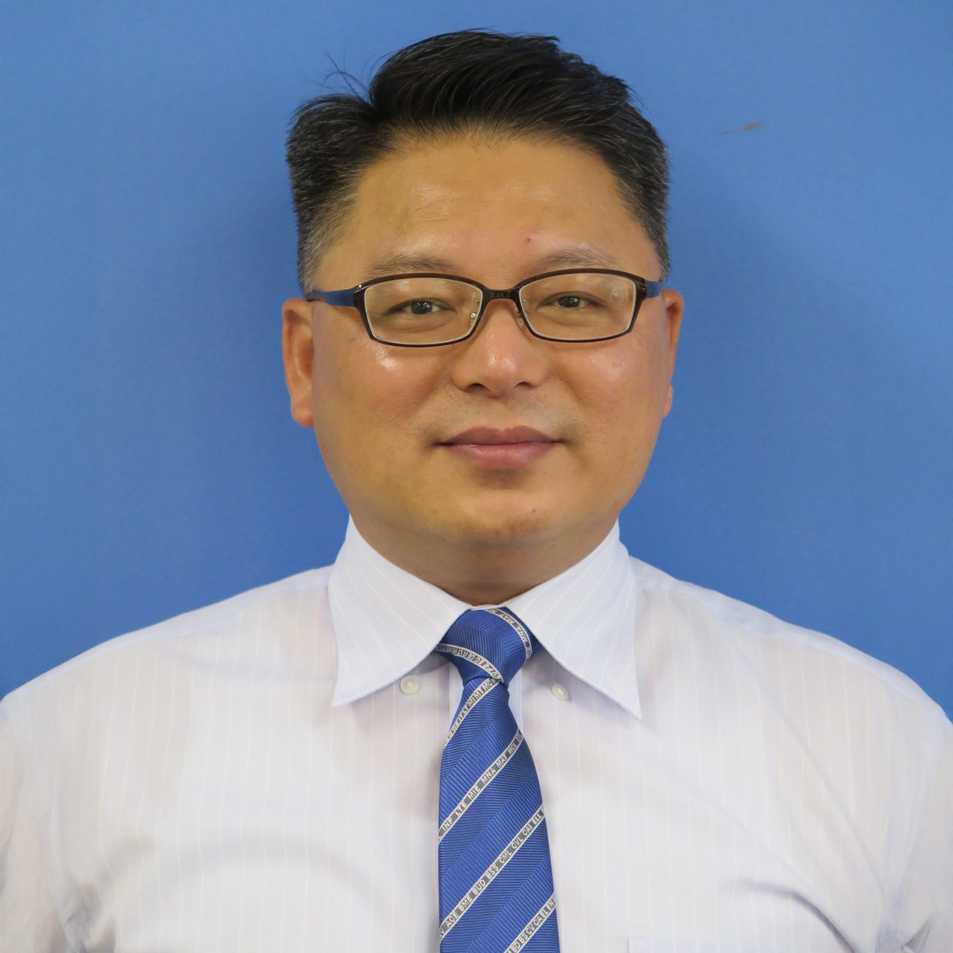 Man wearing glasses, white shirt, and blue tie against blue background