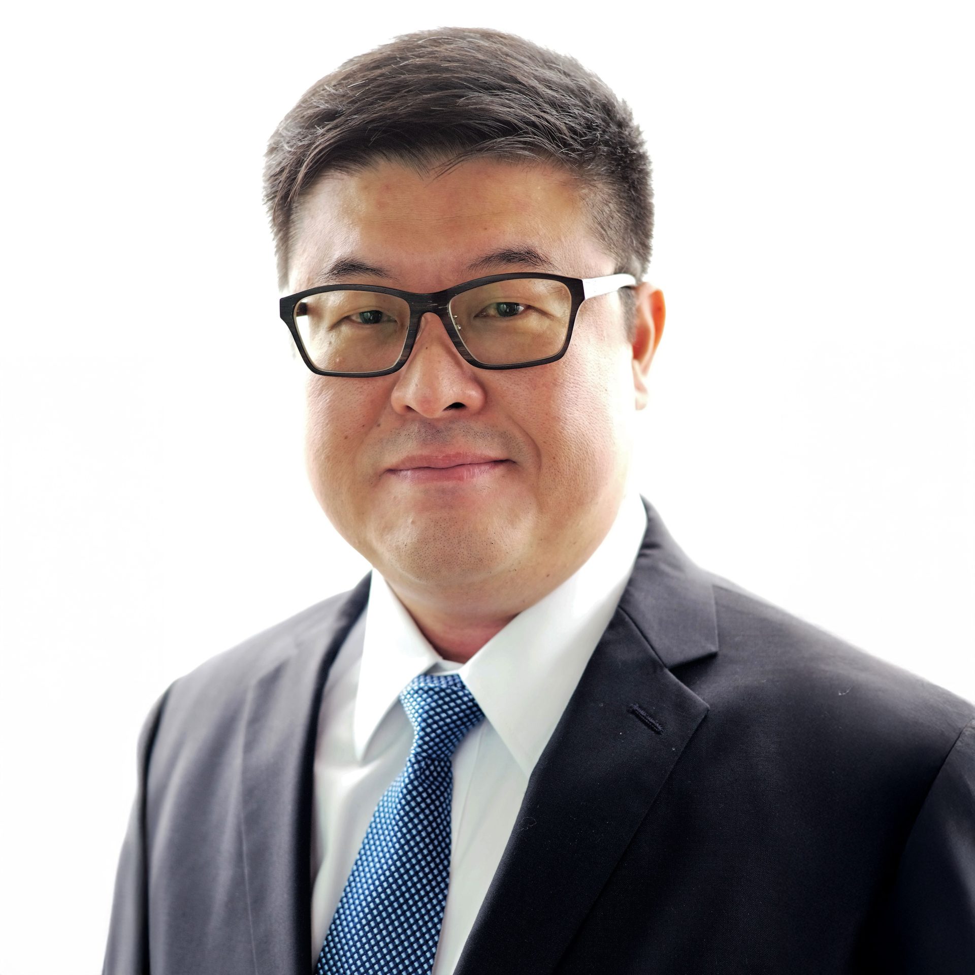 Man in suit and glasses with blue patterned tie against white background
