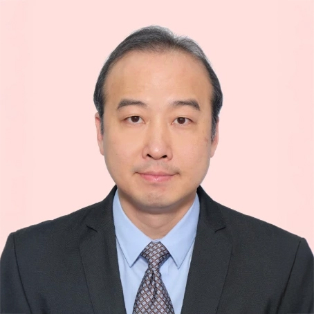 Headshot of a man in a suit and tie against a light pink background.