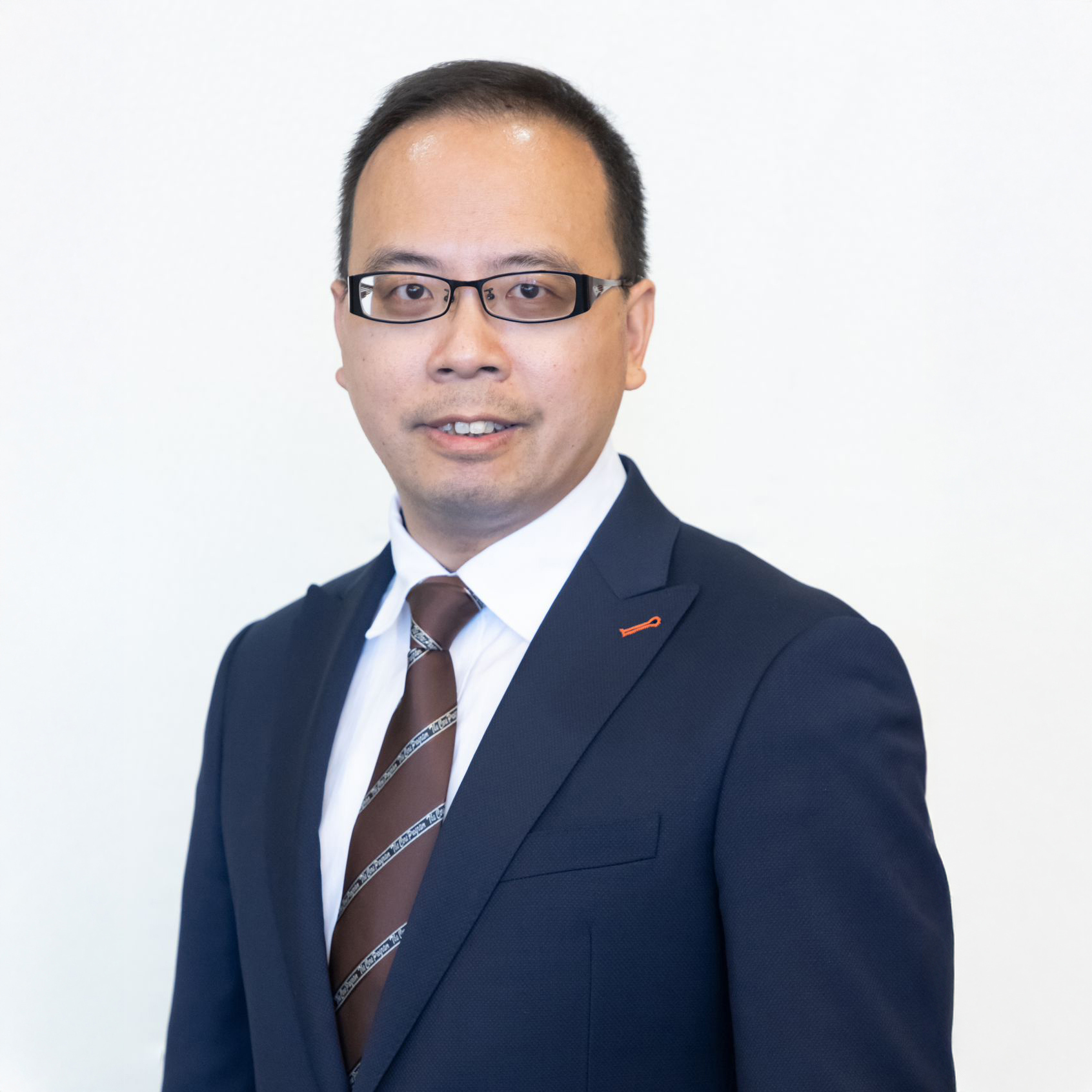 Man in dark suit and glasses smiling at camera