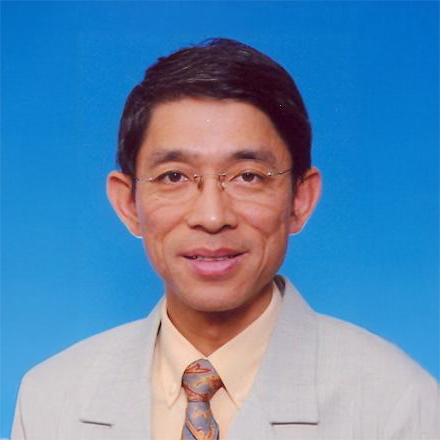 Portrait of a smiling man with glasses wearing a light suit and patterned tie against blue background.