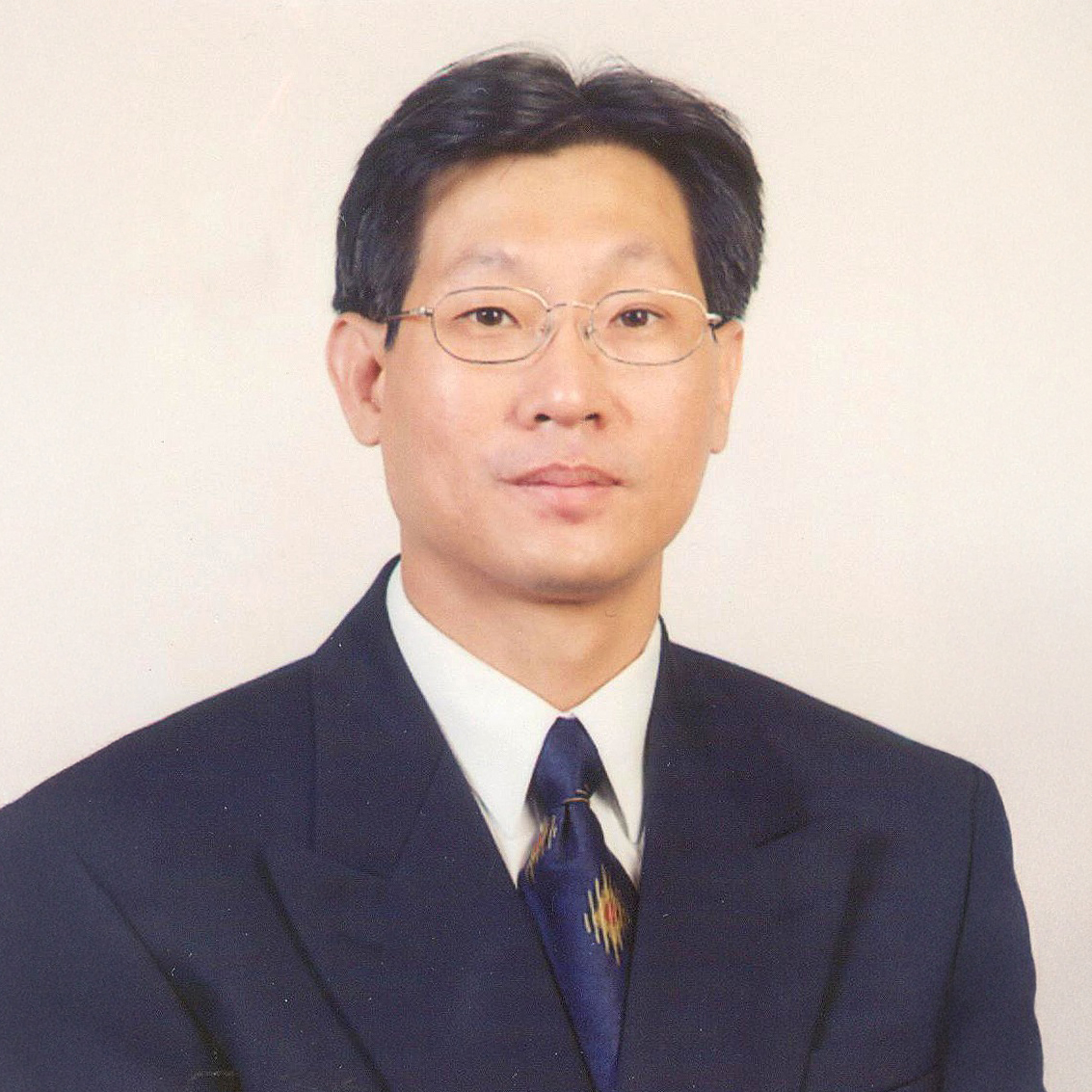 Man in suit and glasses wearing patterned tie