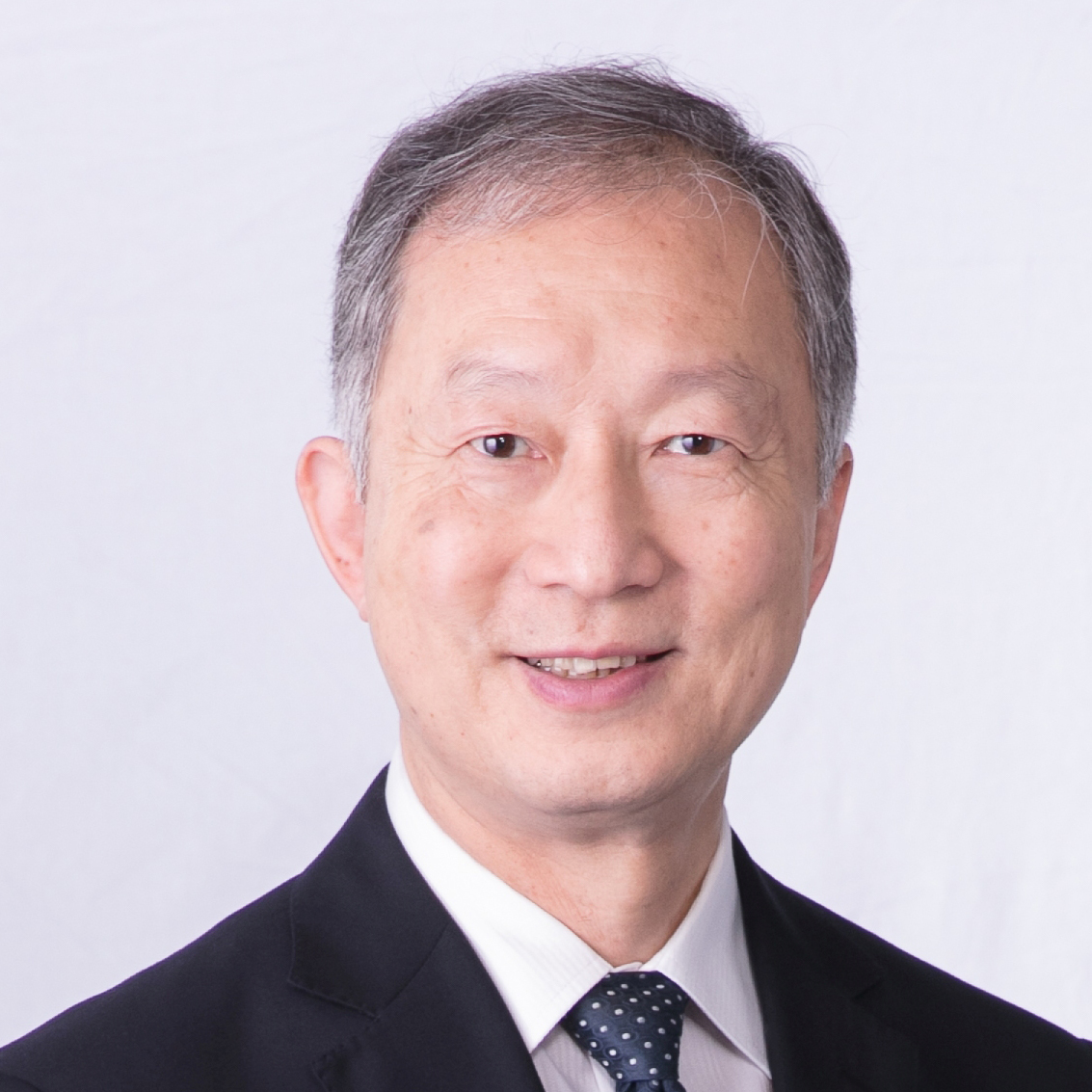 Headshot of a smiling East Asian man in a suit and polka dot tie.