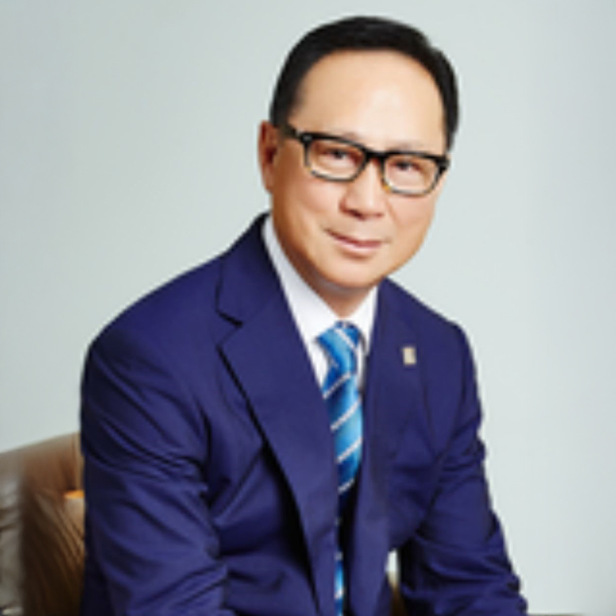 Man in blue suit and glasses smiling at camera