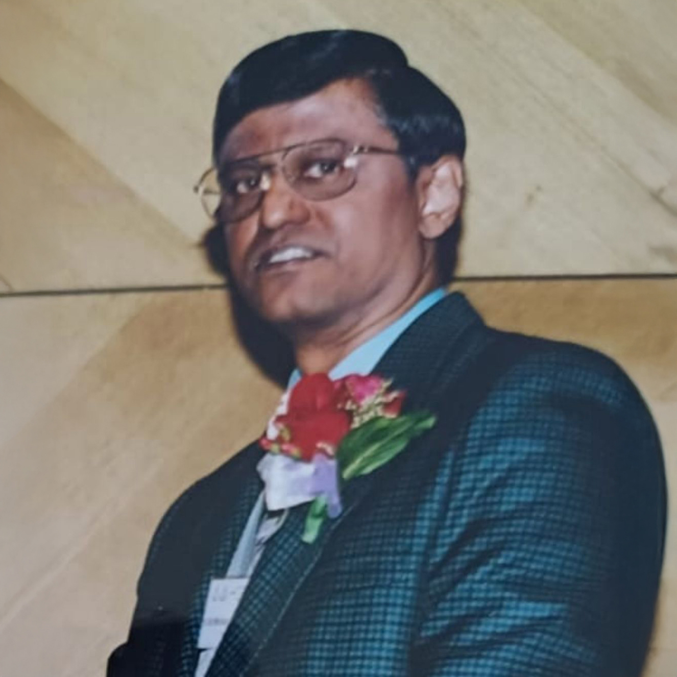 Man in suit with glasses and floral boutonniere at event