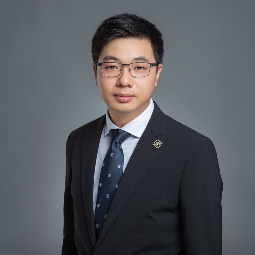 Professional headshot of a man in a suit and glasses.