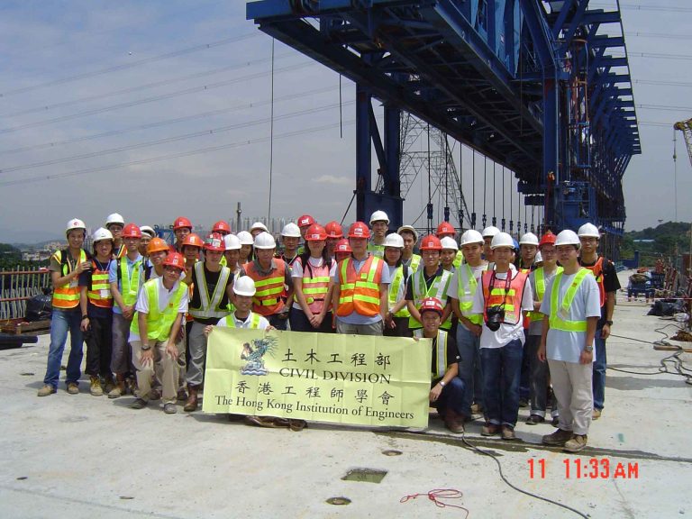 Group of civil engineering students and professionals posing with banner at construction site.