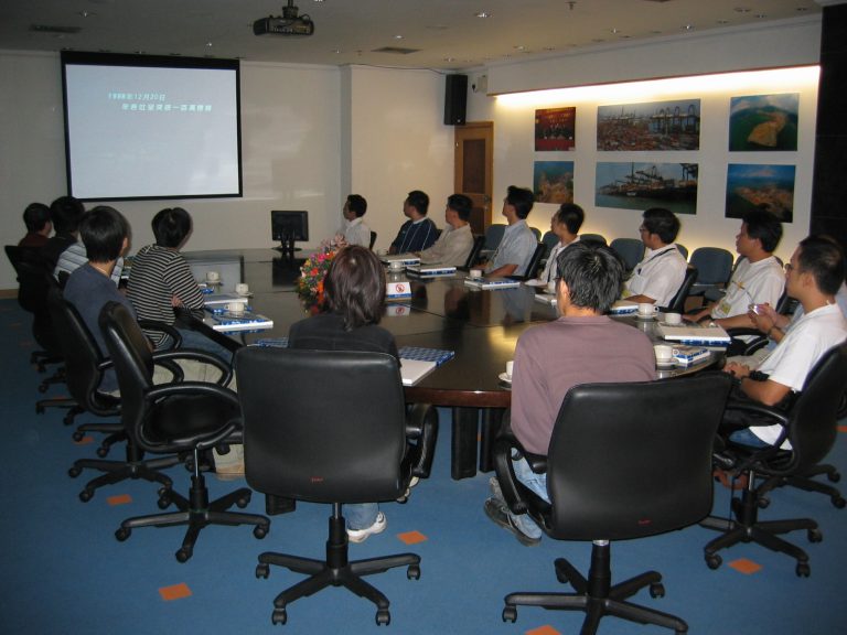 Group meeting in conference room with presentation screen and wall displays.