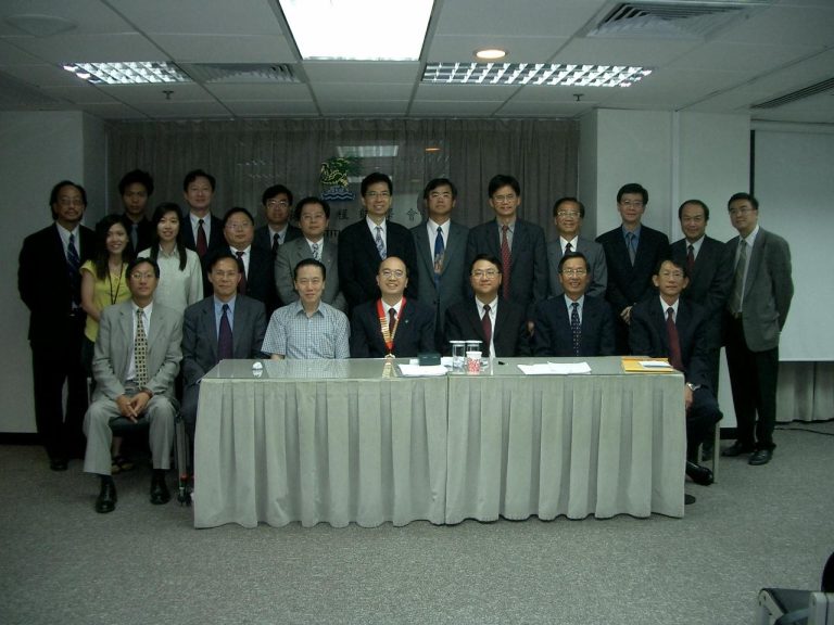 Group of professionals posing for a formal meeting photo in an office setting.
