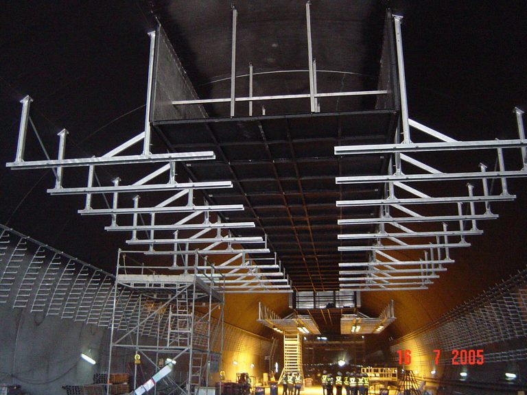 Metal scaffolding structure inside a large industrial or construction facility at night.