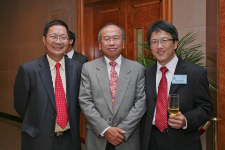 Three men in suits smiling for a photo at an event
