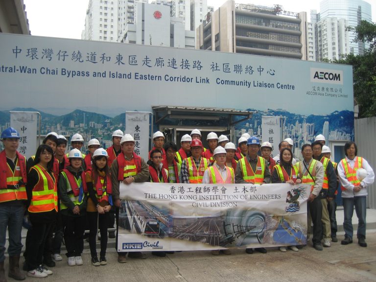 Group of civil engineers and students posing with HKIE Civil Division banner at construction site.