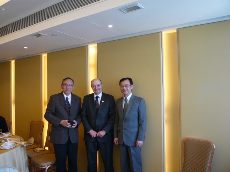 Three men in suits posing for a photo at an event