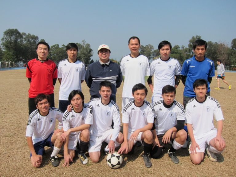 Soccer team posing with coach and ball on field