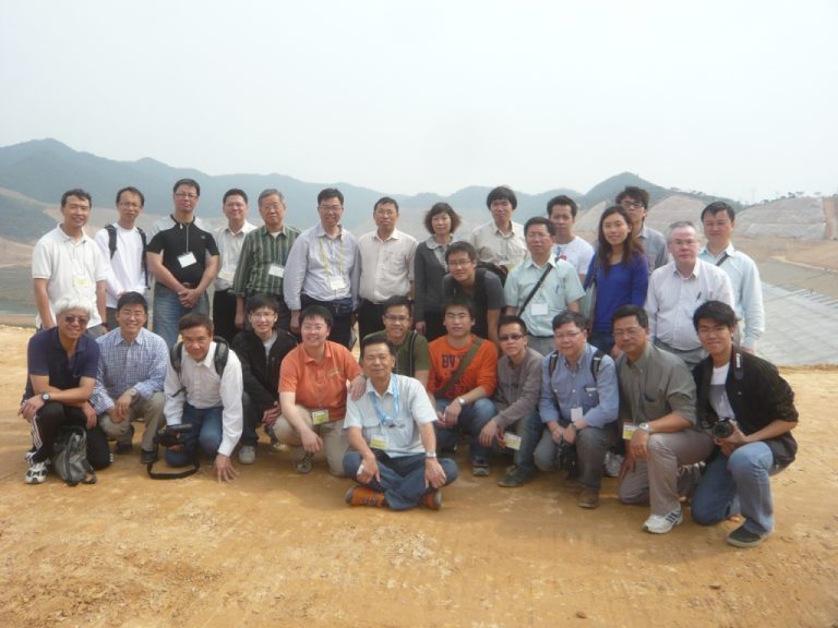 Group of people posing for photo outdoors with mountains in background