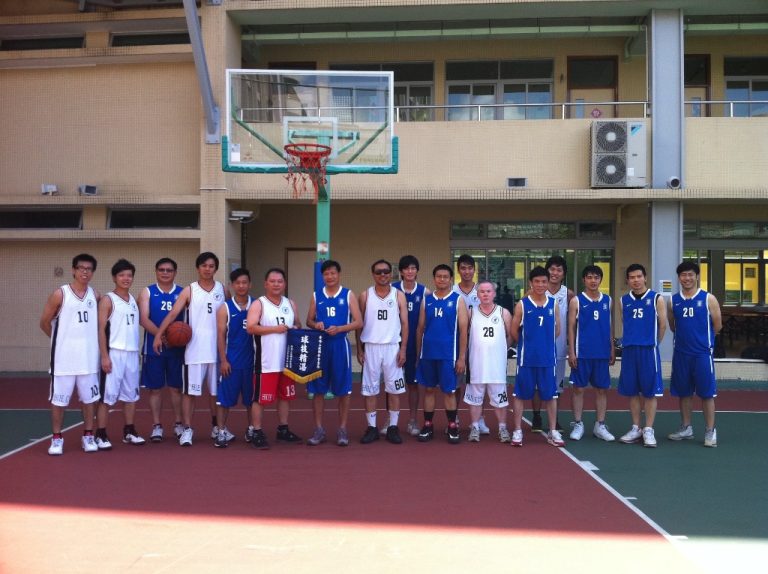 Basketball team posing on court with coach holding banner and player holding ball