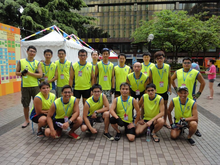 Group of men in yellow athletic vests posing for photo outdoors at event