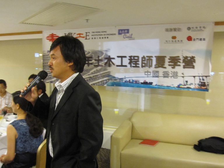 Man speaking into microphone at civil engineering summer camp event in Hong Kong.